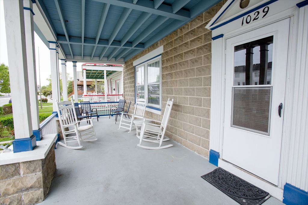 Stacked front porch with rocking chairs and sky-blue beams at Azure Estate