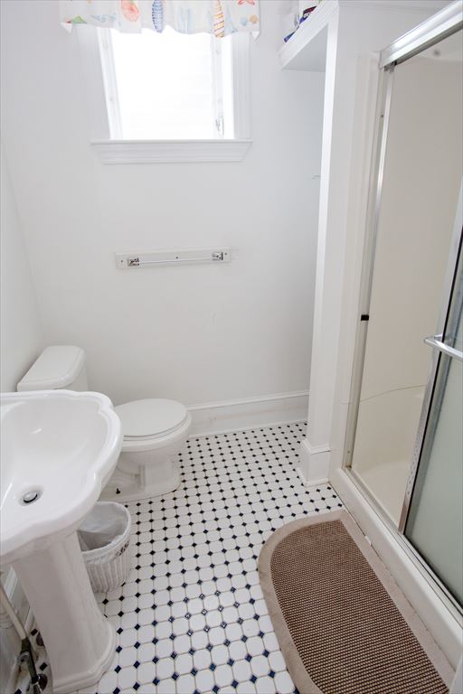 Compact bathroom with a glass-door corner shower stall, a white pedestal sink and a black-and-white octagonal tile floor