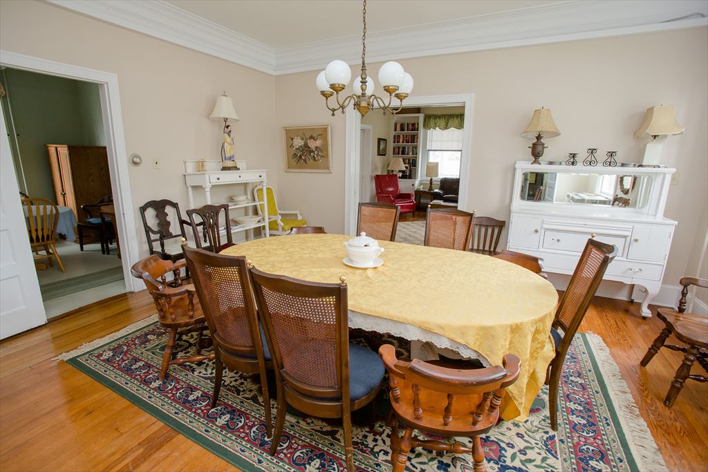 Dining room from another angle showing the oval table, a white sideboard with mirror and open doorways into the living areas